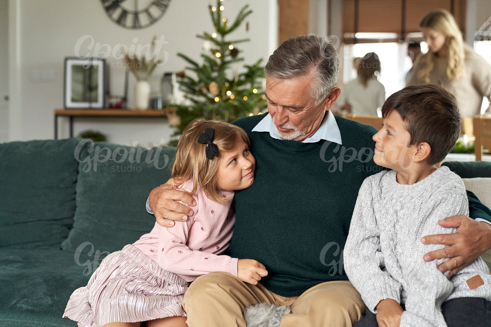 Grandfather and grandchildren bonding on sofa at Christmas time