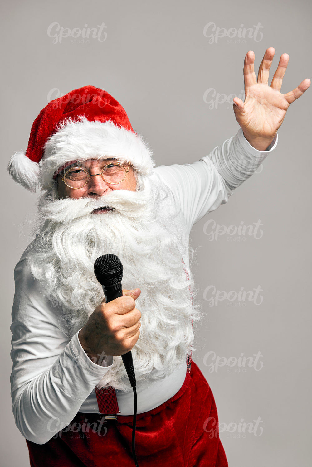 Caucasian Santa Claus singing and dancing on the grey background 