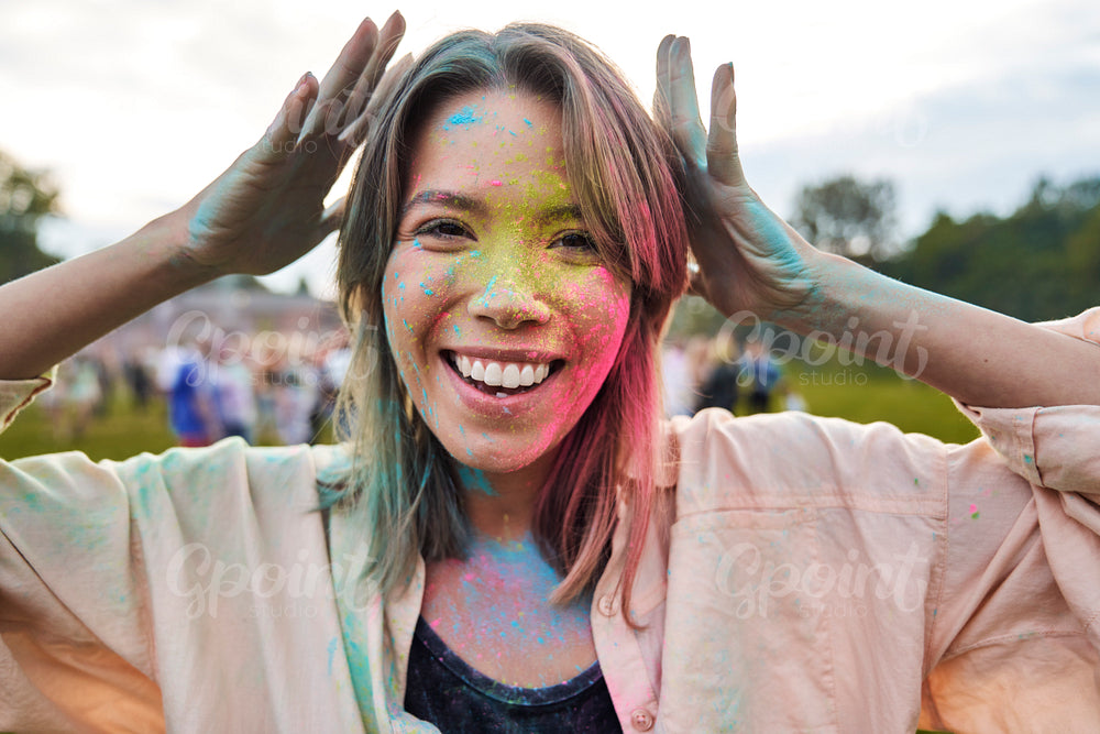 Face of smiling woman with coloured powder at Holi Festival  