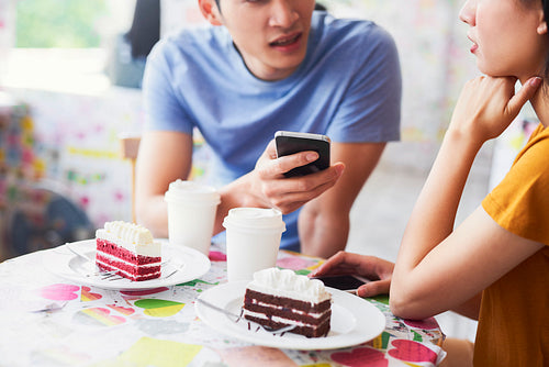Close up of couple using mobile phone in a cafe