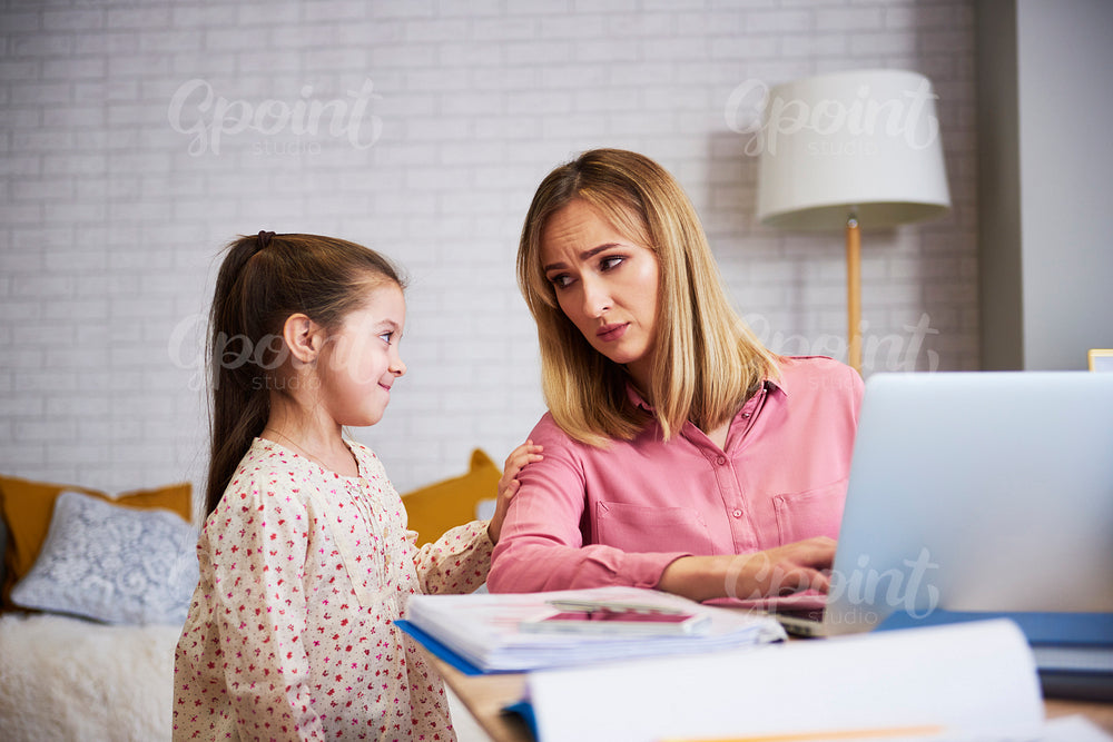 Bored girl with hard working young mummy at home office