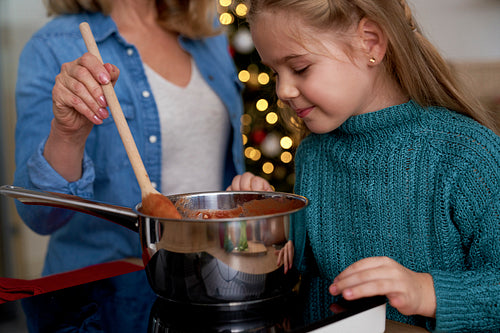 Close up of little girl peeking into a pot while cooking