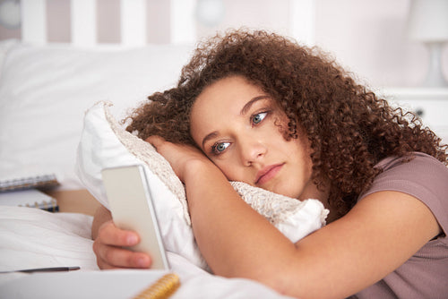 Worried teenage girl lying on the bed