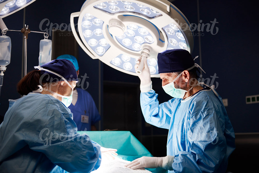 Mature surgeon setting the surgical light during an operation