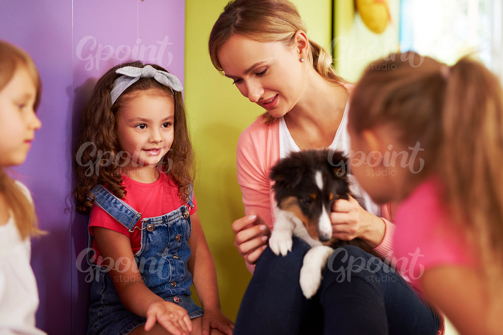 Teacher and children looking after the dog in the preschool