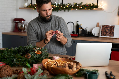 Man learning to decorate a Christmas wreath using decorative ribbon