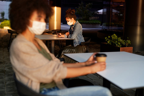 People in face mask sitting alone in a cafe outdoors