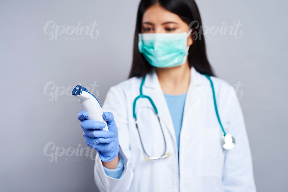 Female doctor looking at non-contact thermometer