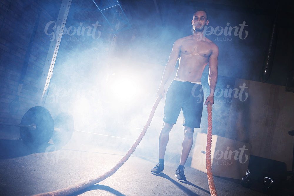 Young man doing crossfit training with ropes
