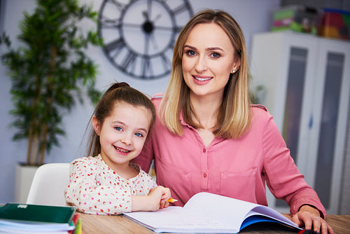 Portrait of smiling mother and child doing homework at home