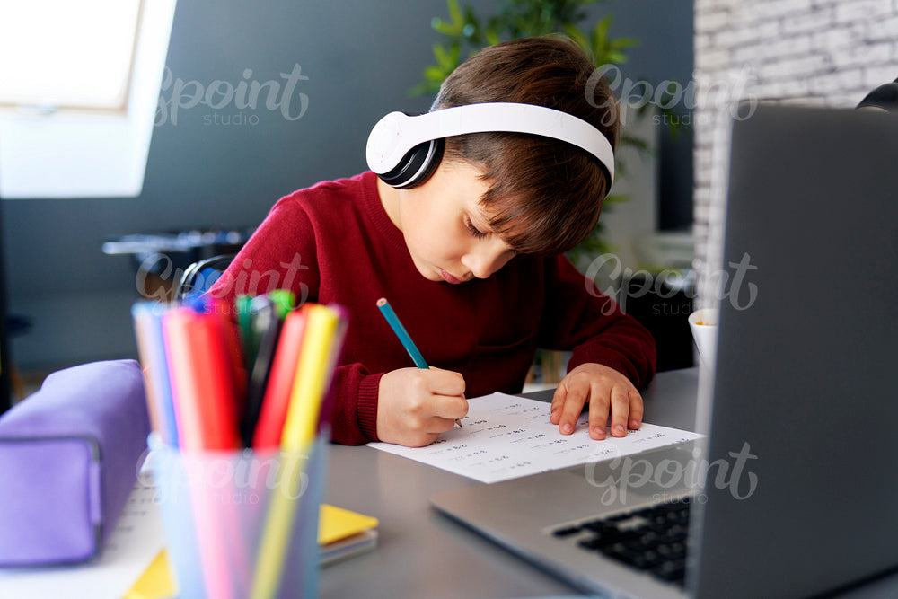 Schoolboy diligently doing homework in his room