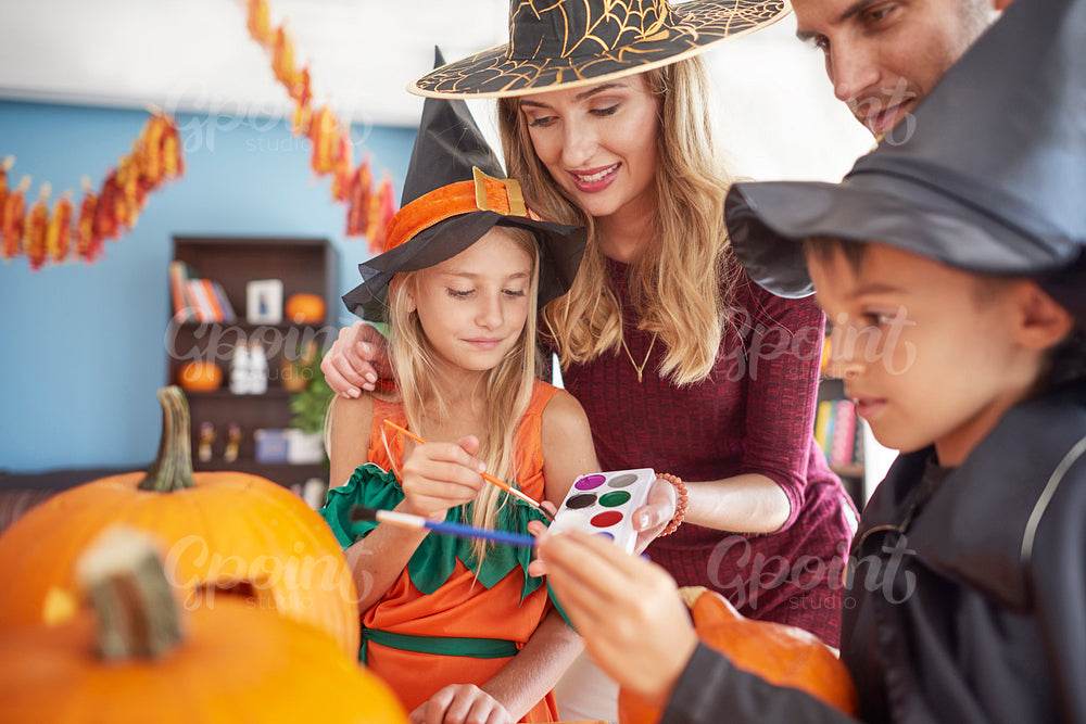 Kids with parents painting Halloween pumpkins