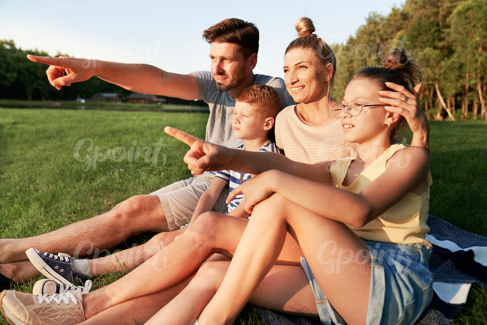 Family pointing at the sunset by the lake