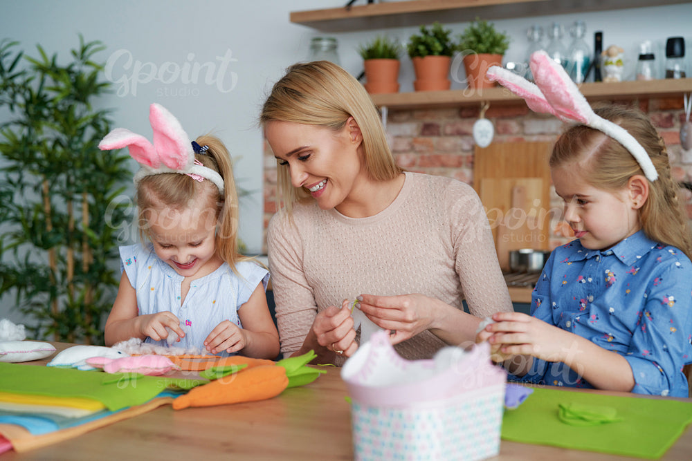 Happy mother and daughters preparing Easter decorations at home