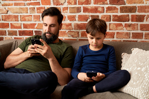 Father and son spending time with mobile phone at home