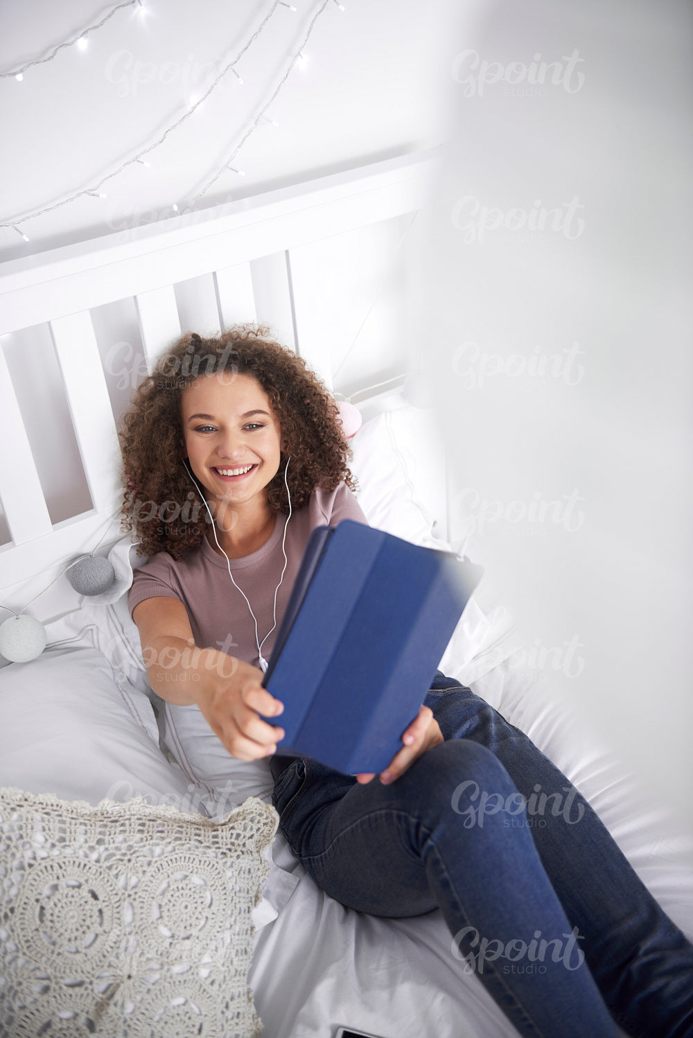 Smiling teenage girl making a selfie in her bed