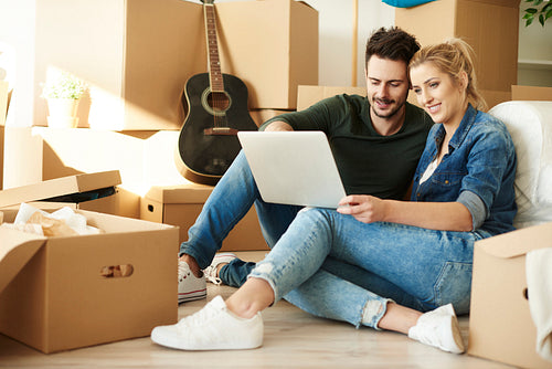 Couple with laptop around cardboard boxes
