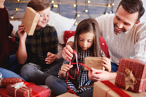 Happy children opening christmas present with parents