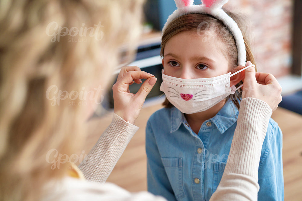 Mom applying on a protective mask for her daughter