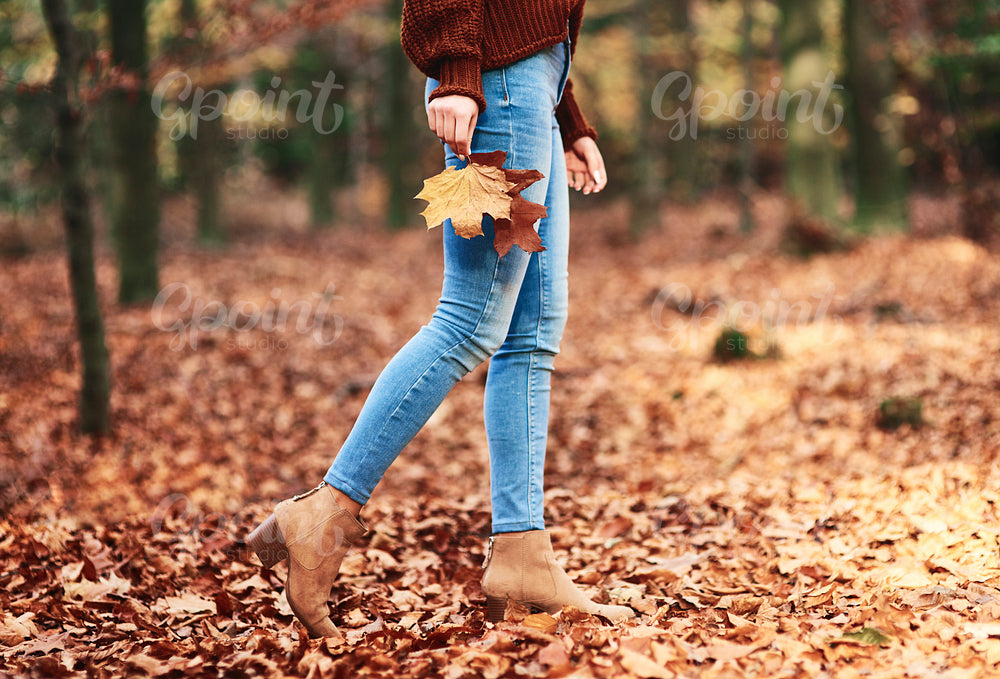 Low section of woman walking in autumn forest