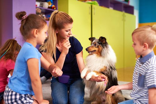Young woman and her dog playing with children during therapy