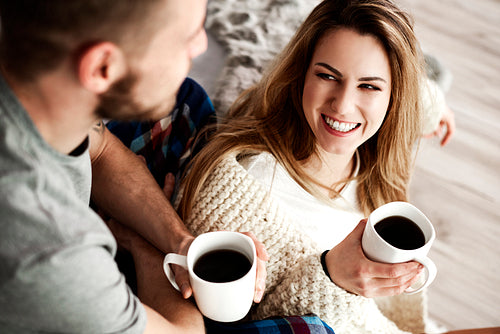 Couple with coffee talking in bedroom