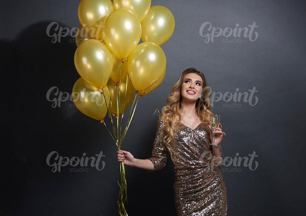 Woman with balloons and champagne looking at copy space