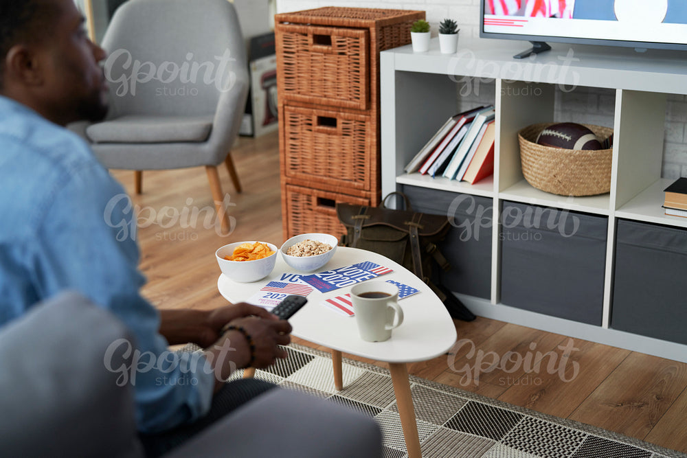 Detail of information leaflets and man watching TV