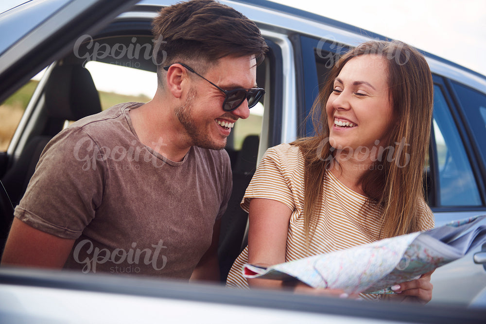 Young couple reading a map during road trip