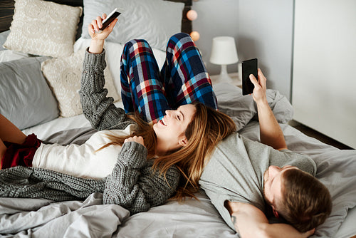 Couple using mobilephone in bed