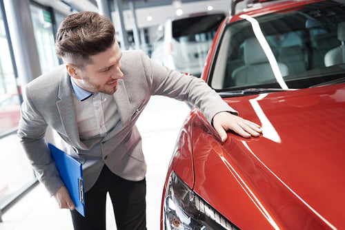 Car salesman examining vehicle before selling