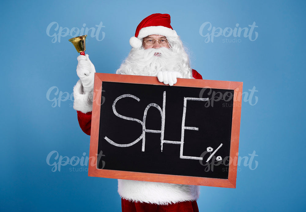 Portrait of santa claus holding blackboard and bell