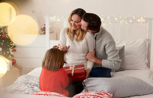 Happy family with Christmas gift in bed