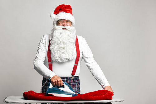 Caucasian Santa Claus ironing trousers for Christmas