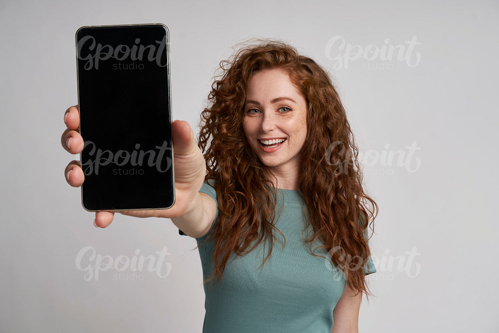 Redhead showing screen of mobile phone 