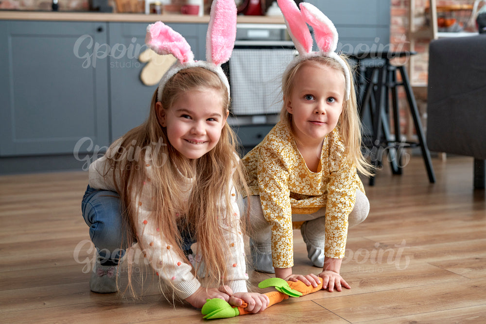 Two happy girls playing handmade carrots on the floor