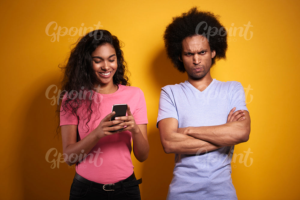 Jealous man and his girlfriend with a mobile phone