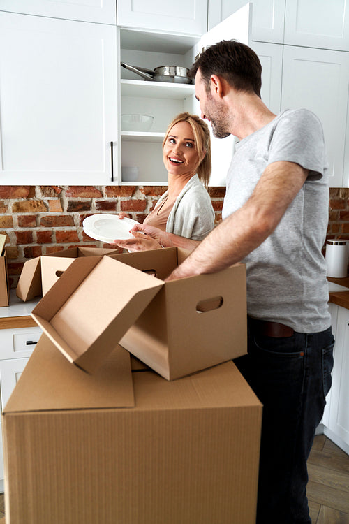 Couple during a move pack their things into cardboard boxes