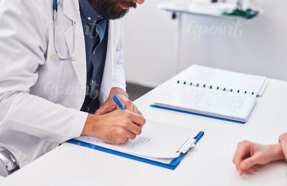 Doctor writing a prescription for his patient