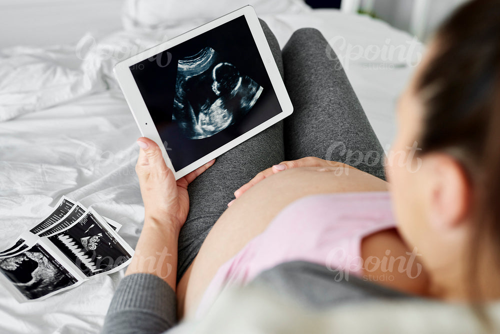 Rear view of pregnant woman browsing ultrasound image on tablet