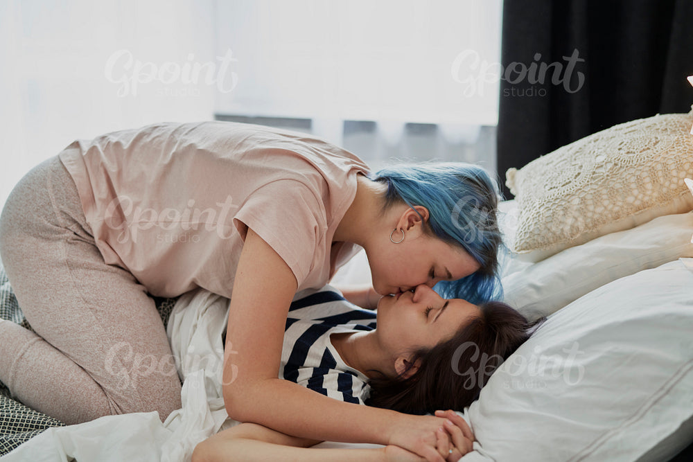 Lesbian couple kissing intimately in bed in the morning