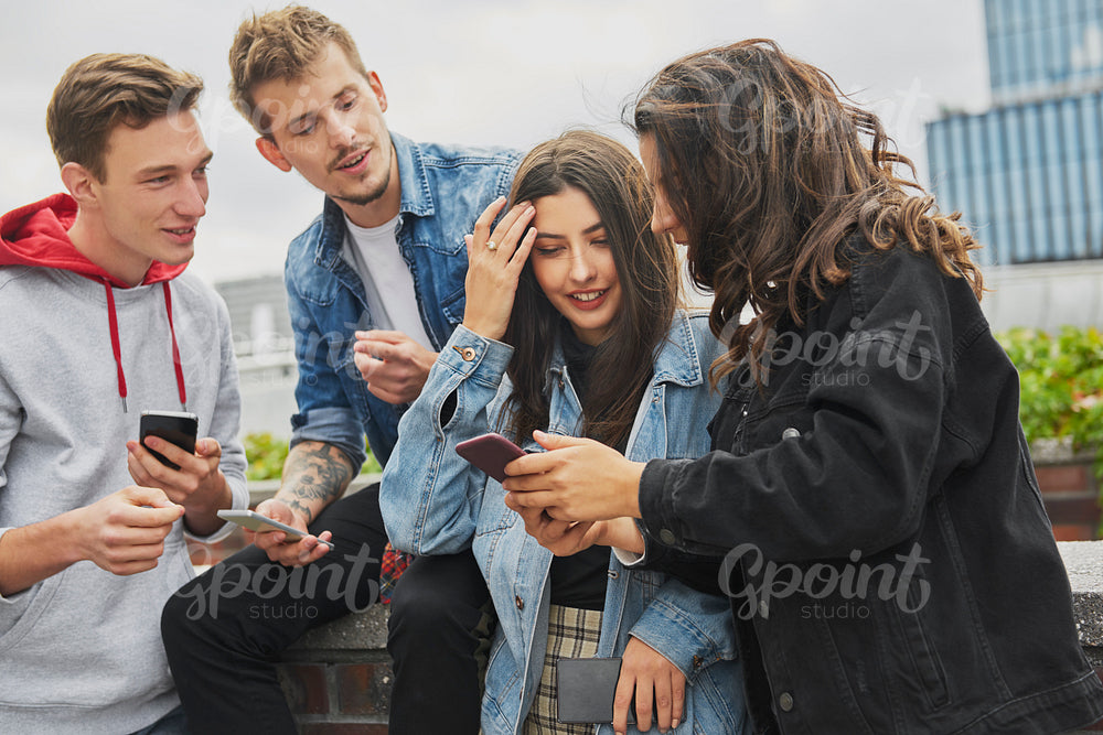 Group of friends using their mobile phone in the city