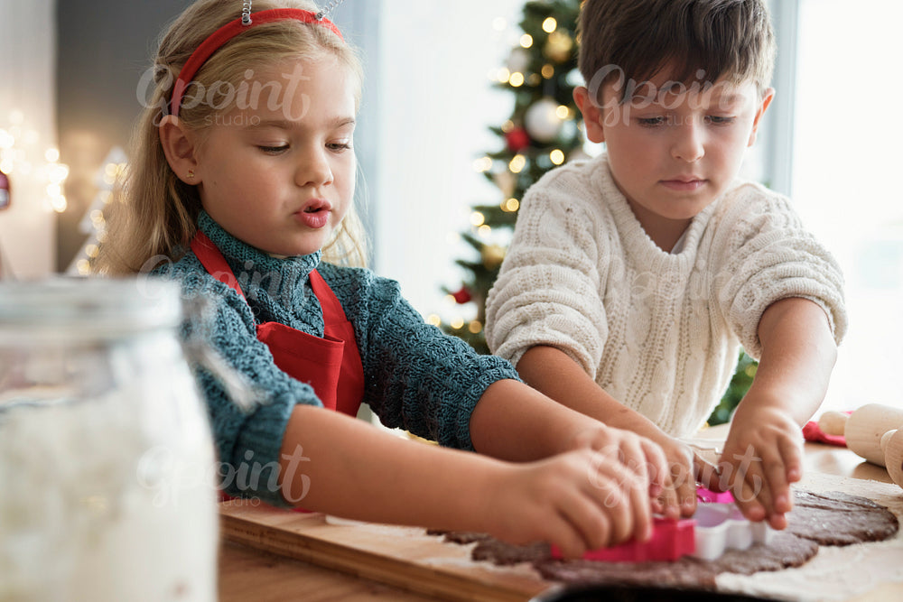 Two children cutting out gingerbread cookies