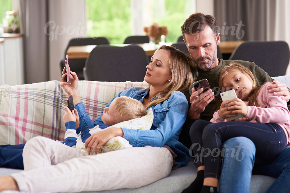 Parents and children using mobile phone in living room