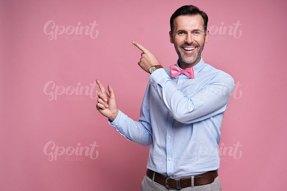 Smiling man showing at pink wall
