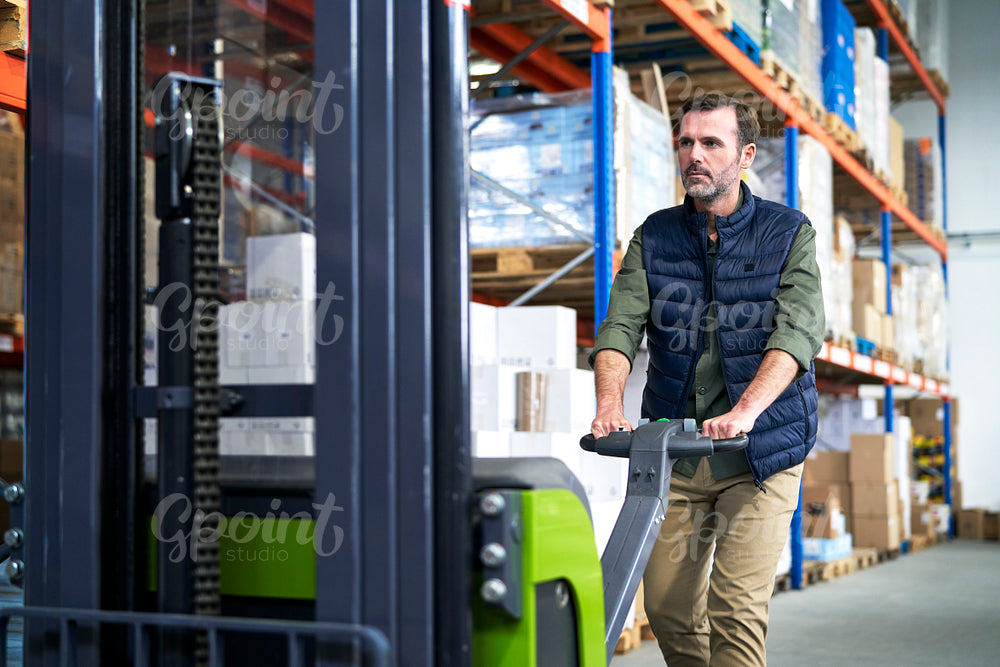 Adult caucasian man working at forklift in warehouse 