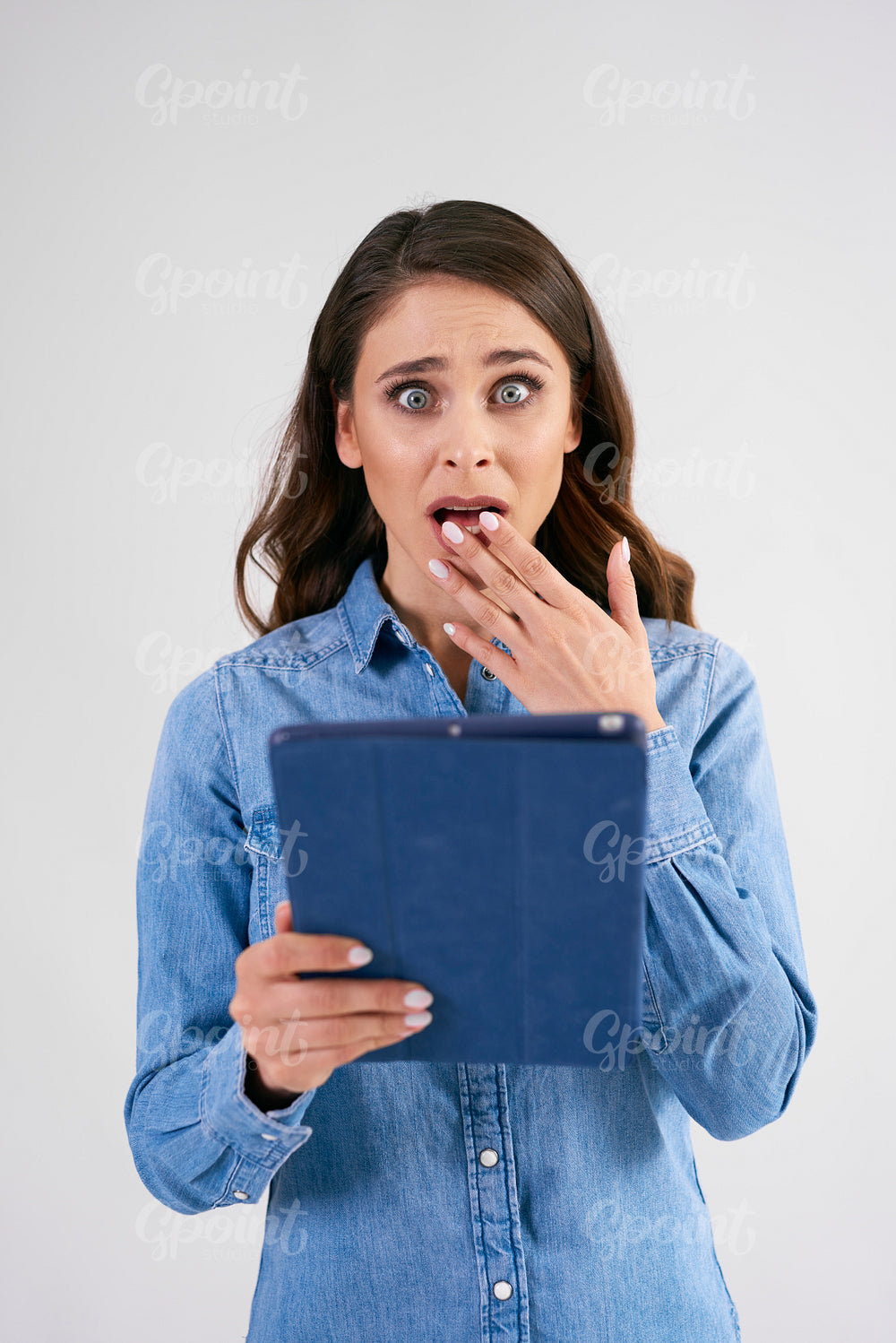 Shocked woman with tablet in studio shot