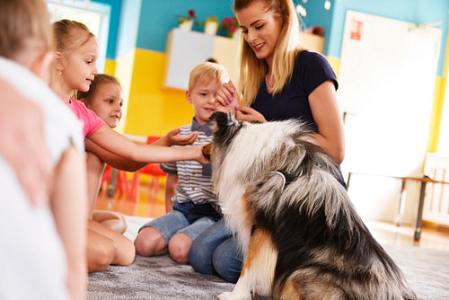 Young woman and her therapy dog working with children