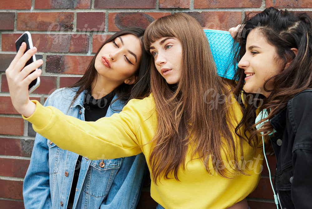 Three girls making a selfie by mobile phone