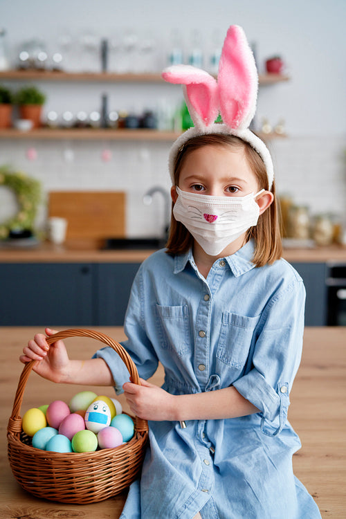 Portrait of girl in a protective mask with Easter basket
